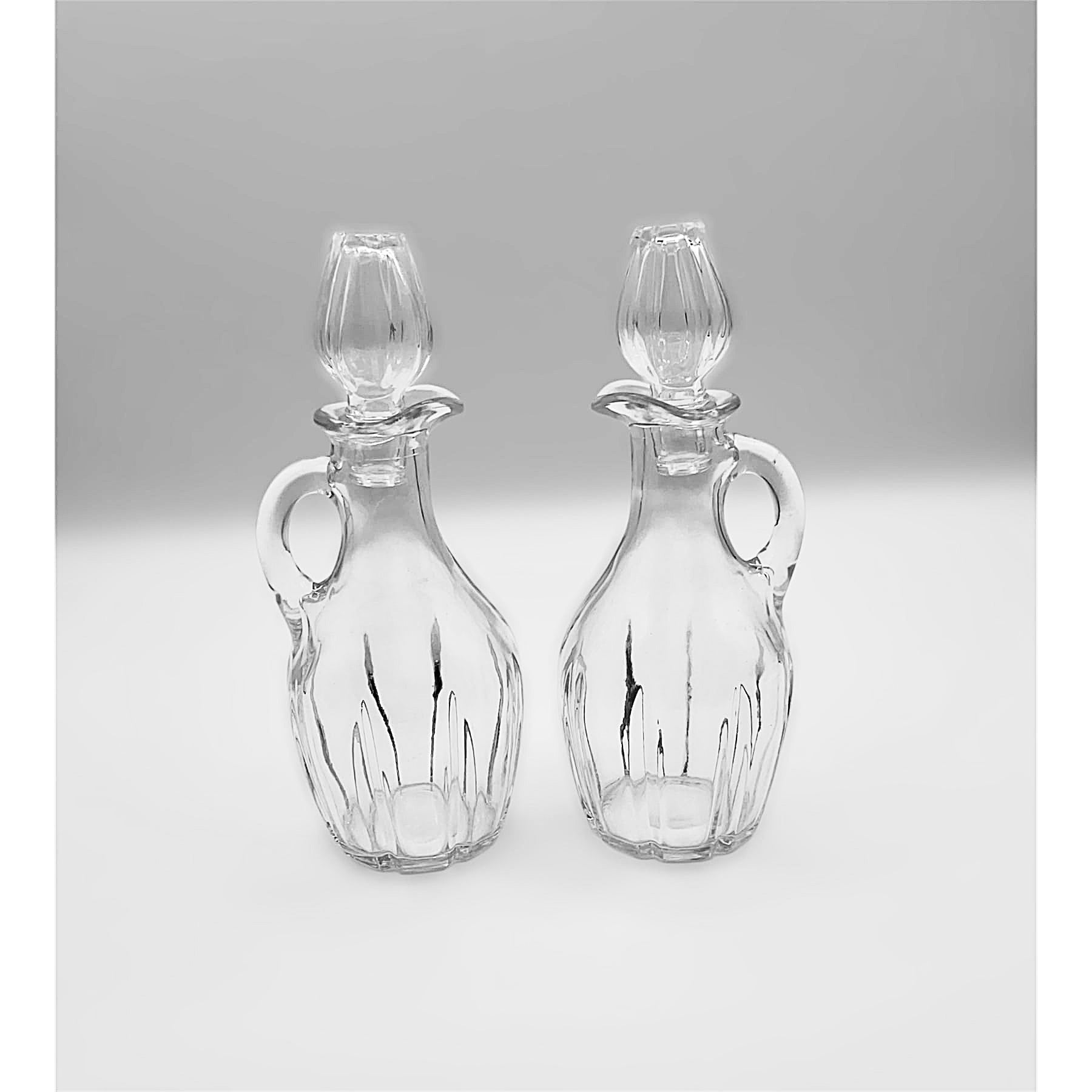 Ampolle con manico e tappo in vetro trasparente, set of two clear glass bottles with handles and stoppers.